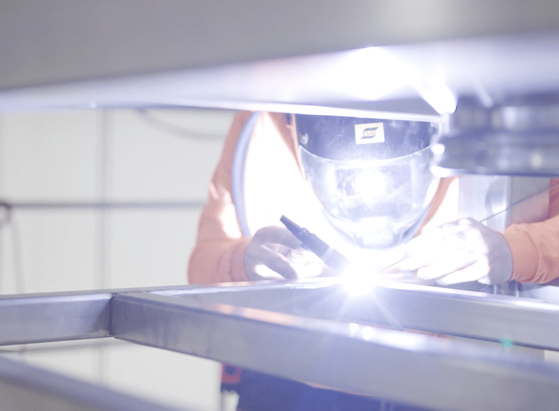 Man welding a support from for processing equipment